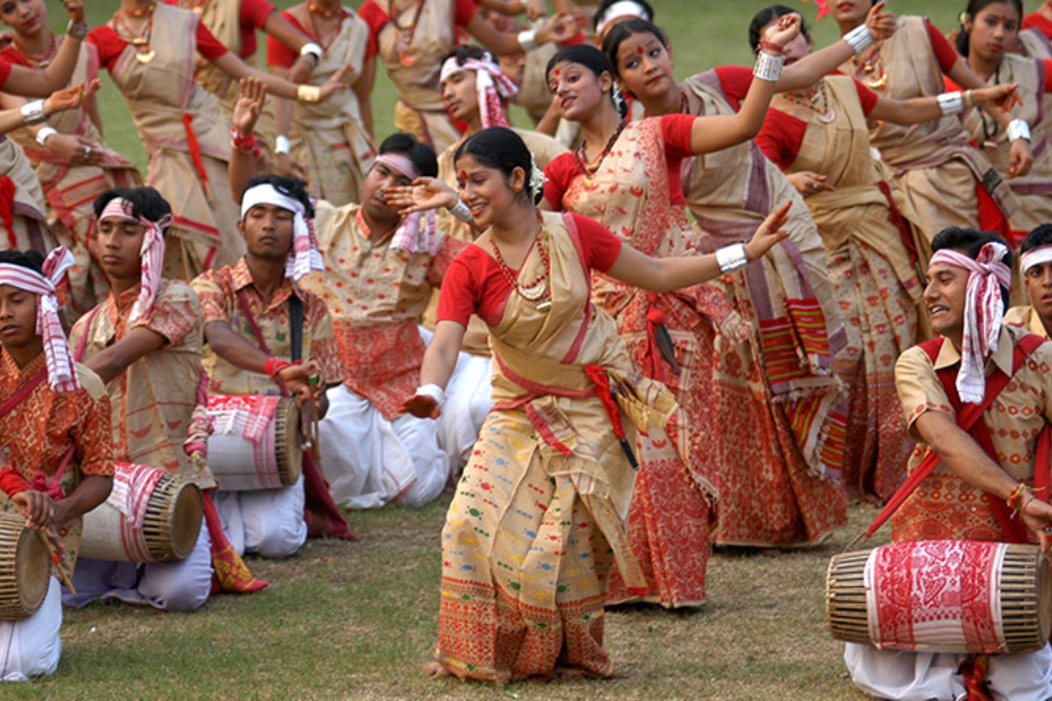 Group of Bihu dancers performing in traditional formation with live dhol accompaniment