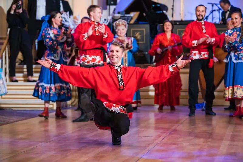 Russian dance group in coordinated traditional costumes performing synchronized choreography on stage